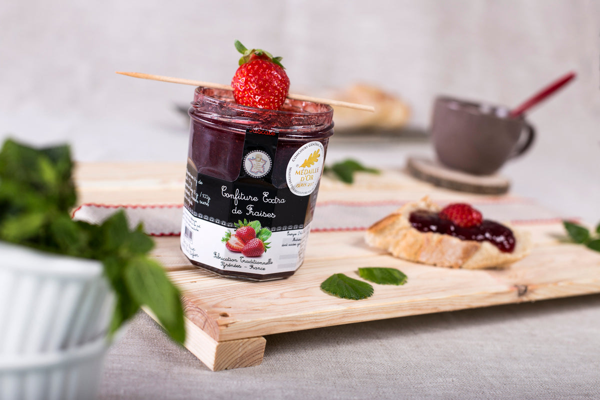 Pot de confiture extra de fraises Maison JOUGLA avec une fraise et une tartine.